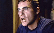 a man in a blue shirt is making a funny face with his mouth open