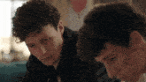 two young men with curly hair are looking down at something
