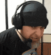 a man wearing headphones and a hat is looking at something