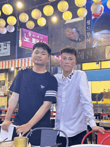 two young men pose for a photo in front of a sign that says 5000 2f
