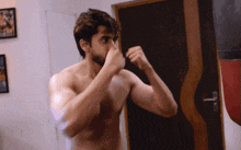 a man without a shirt is standing in front of a boxing bag