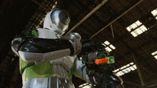 a man in a green and white costume is holding a gun in a warehouse
