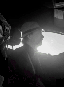 a man in a hat sits in a car with a woman in the back seat