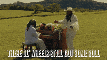 a man playing a piano in a field with the words " these ol wheels still got some roll " below him