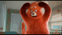 a red teddy bear is standing in a room with regal written on the bottom