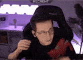 a man wearing glasses is sitting in a gaming chair in front of a computer .