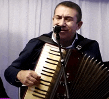 a man singing into a microphone while playing an accordion with the letter e on it