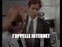 a man and a woman are standing next to each other and the woman is talking to the man in a suit and tie .