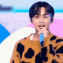 a young man is singing into a microphone on a stage .