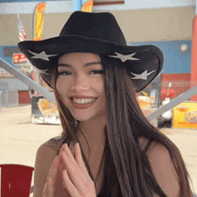 a woman wearing a black cowboy hat with stars on it smiles