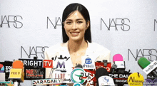 a woman stands in front of a wall with nars on it