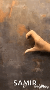 a hand is making a heart shape with its fingers on a table .