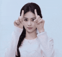 a woman in a white sweater with a heart on it is pointing upwards
