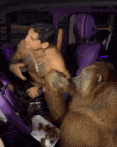 a shirtless man sitting in a purple car with a monkey