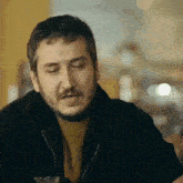 a man with a beard and mustache is wearing a black jacket