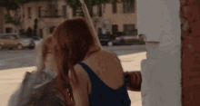 a woman in a blue tank top is kissing another woman on the cheek