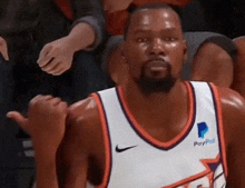 a basketball player wearing a paypal jersey is giving a thumbs up