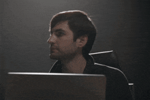a man in a suit is looking at a laptop