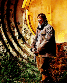 a man in a brown jacket and scarf is standing in front of a large circular object