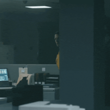 a man in a yellow shirt stands in a dark room