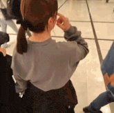 a woman in a gray sweater is standing in a crowd