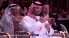 a man sitting in a chair with arabic writing on the screen