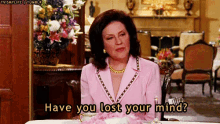 a woman in a pink jacket is sitting at a table and says have you lost your mind