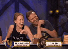 a man and a woman are laughing while sitting at a table with the names caleb and beauregard on it