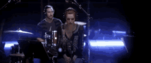 a man and a woman are playing drums and singing into microphones