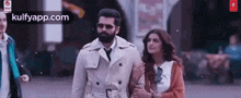 a man and a woman are walking down a city street .