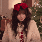 a woman wearing a red bow on her head and a sweater that says ' christmas ' on it