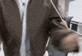 a man in a brown jacket and white shirt is standing in front of a white board .
