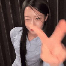 a woman with long black hair winks at the camera while making a peace sign