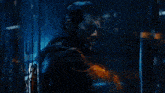 a man is standing in a dark room behind a glass wall .