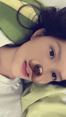 a girl laying on a bed with a fake nose on her face