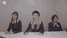 three girls are sitting at a table with the word twice on the bottom right