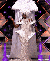 a woman in a white dress is standing on a stage with a purple background .