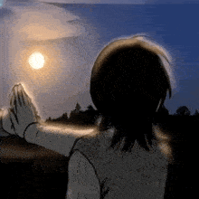 a woman is praying with her hands in front of the moon