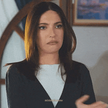 a woman with long dark hair is wearing a black jacket and white shirt .