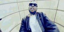 a man wearing sunglasses and a watch is being punched in the face by another man in a room .