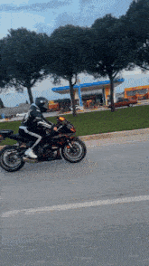 a person is riding a motorcycle down a road in front of a gas station