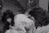a black and white photo of two women sitting next to a statue of a man .