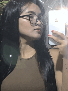 a woman wearing glasses takes a picture of herself in the mirror