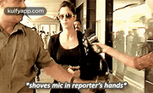 a woman is being interviewed by a reporter while holding a microphone in her hand .