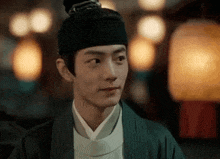 a man in a traditional costume is standing in front of a lantern and looking at the camera .