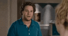 a man in a blue shirt is talking to another man with the words back the fuck off above him .