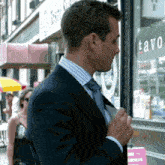 a man in a suit and tie stands in front of a store called tavo