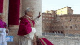 a man in a purple robe is standing in front of a building with the word vatican on it