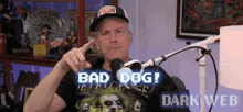 a man in a hat is sitting in front of a microphone and says bad dog .