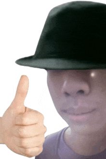 a man wearing a hat gives a thumbs up